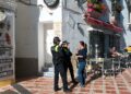 Una mujer conversa con dos policías en una calle de Marbella./ Foto: Vladimirs_Gorelovs / iStock