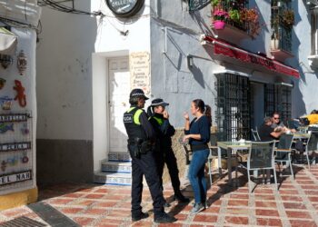 A woman talks to two police officers on a street in Marbella./ Photo: Vladimirs_Gorelovs / iStock