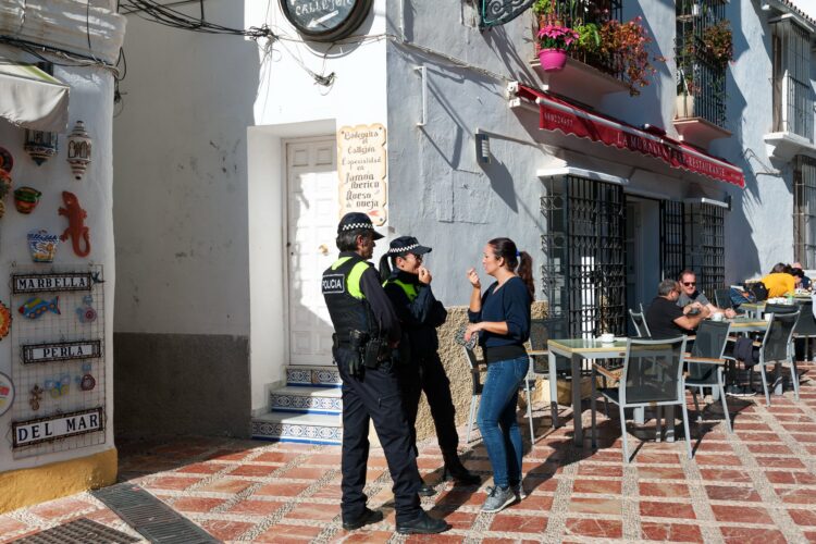 A woman talks to two police officers on a street in Marbella./ Photo: Vladimirs_Gorelovs / iStock